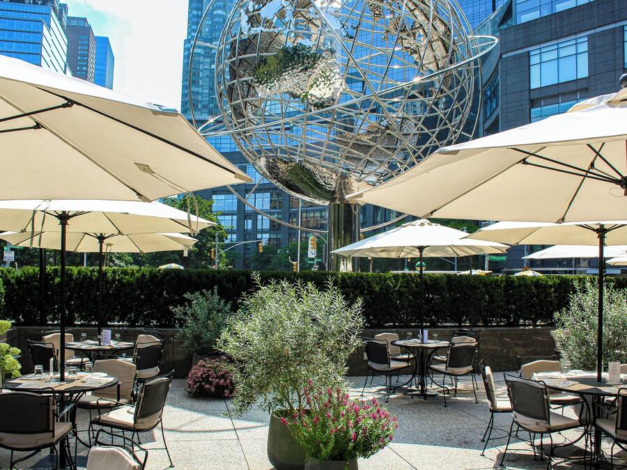 An outdoor seating area with tables and chairs, umbrellas, and a decorative globe sculpture.