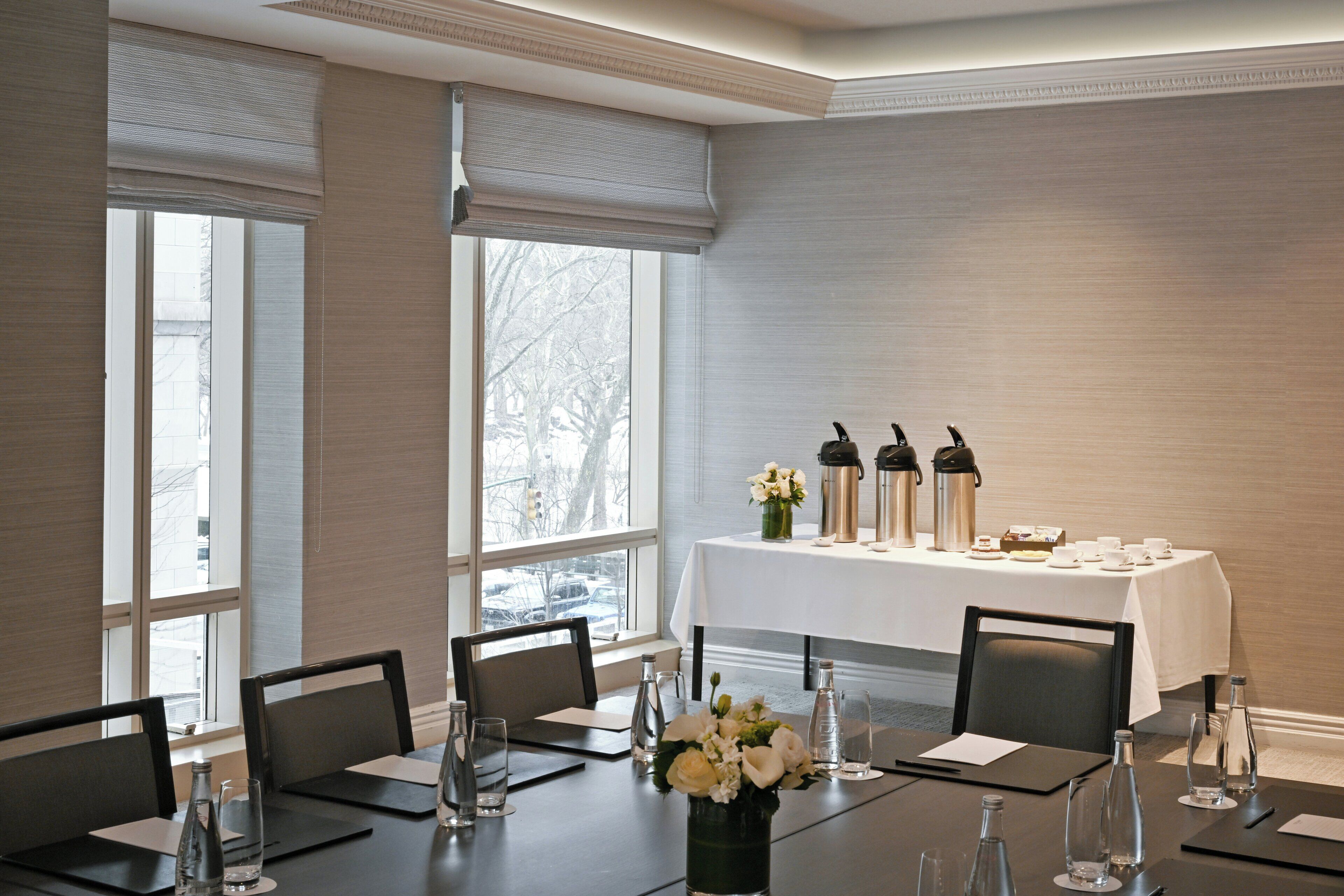 A conference room with a long table, chairs, and a white tablecloth.