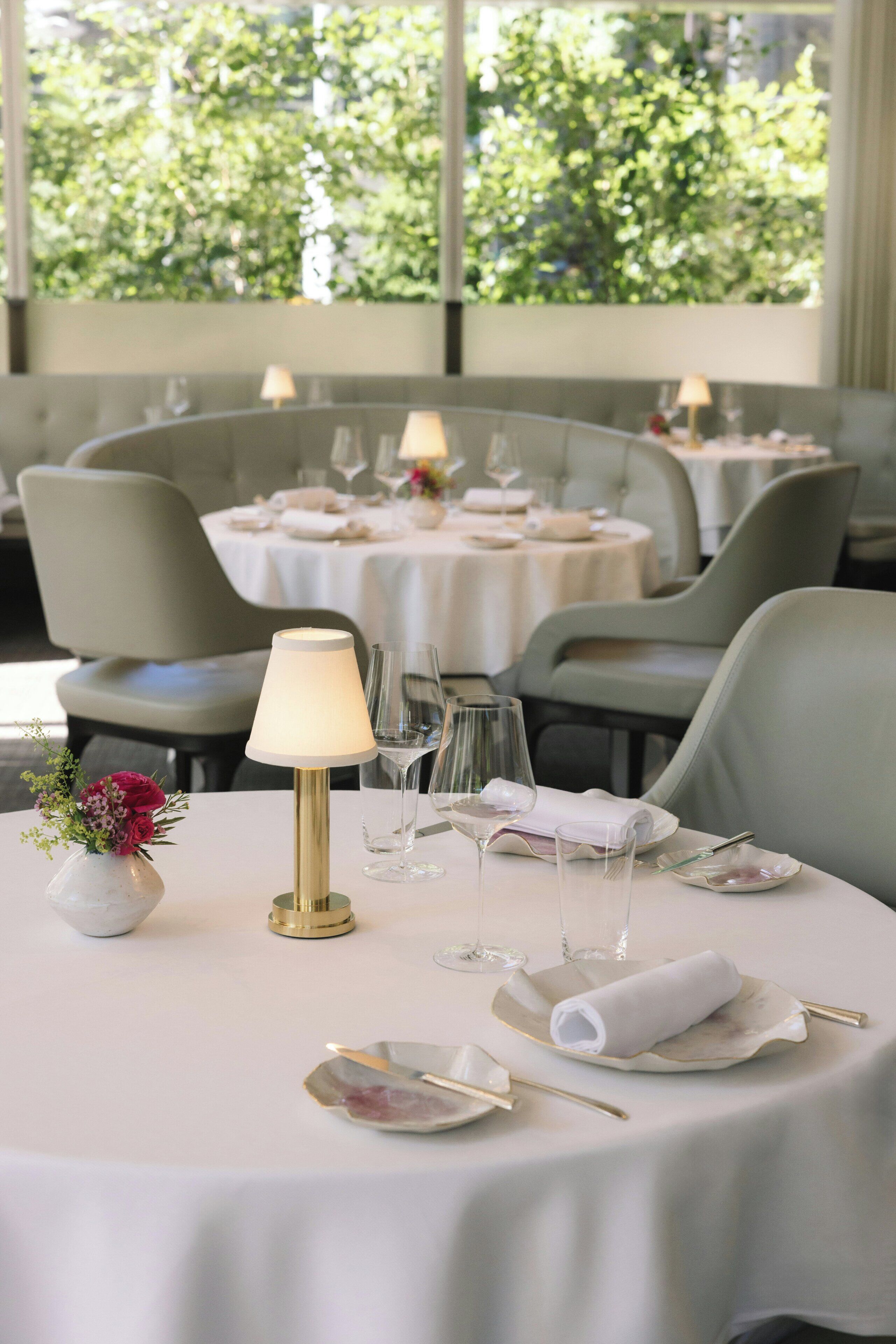 A dining table set with white tablecloth, glassware, and a vase with flowers.