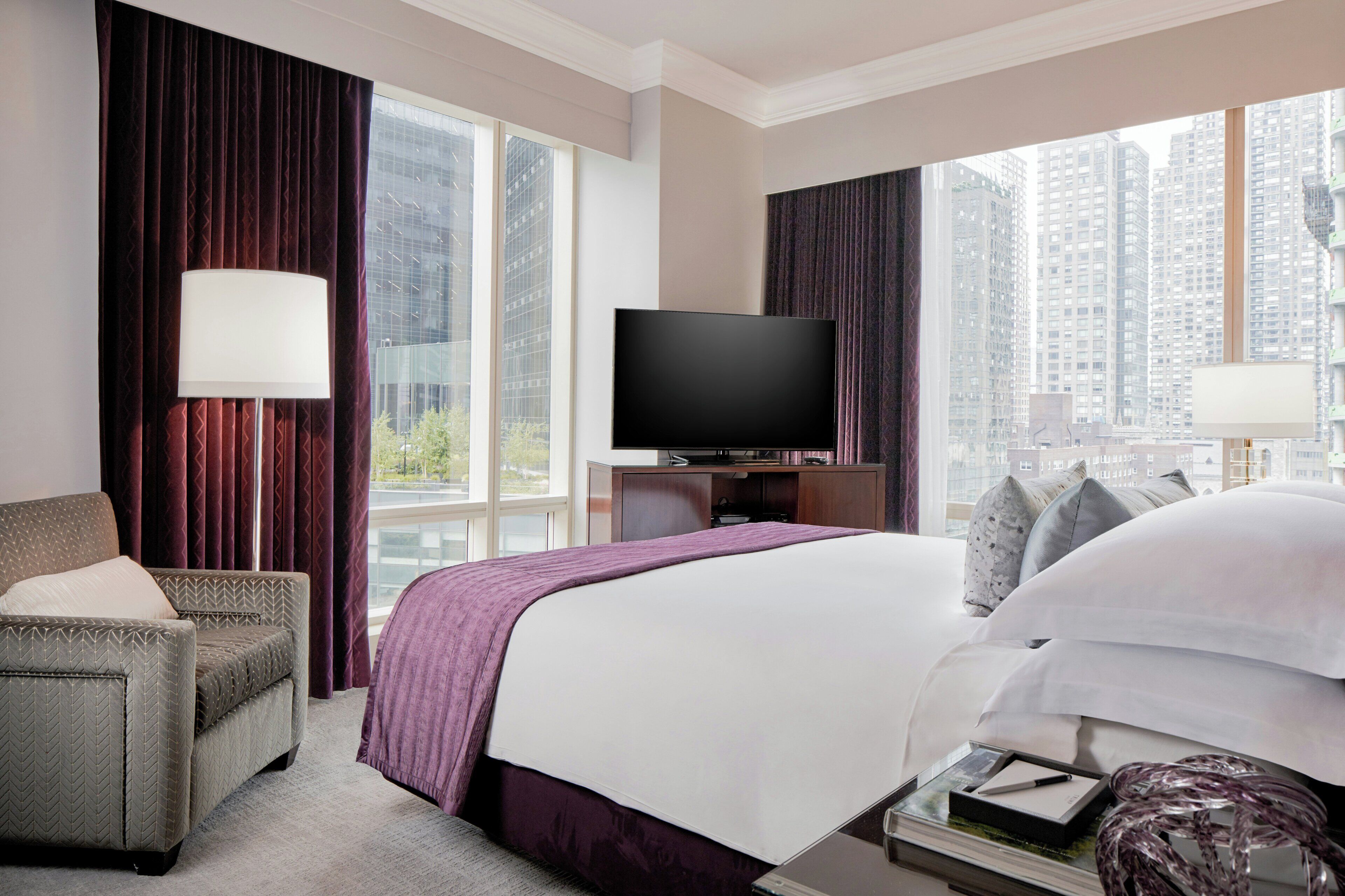 A hotel room with a bed, a television, a desk, and a chair.
