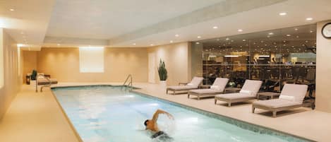 Piscina interna com espreguiçadeiras e equipamentos de ginástica.