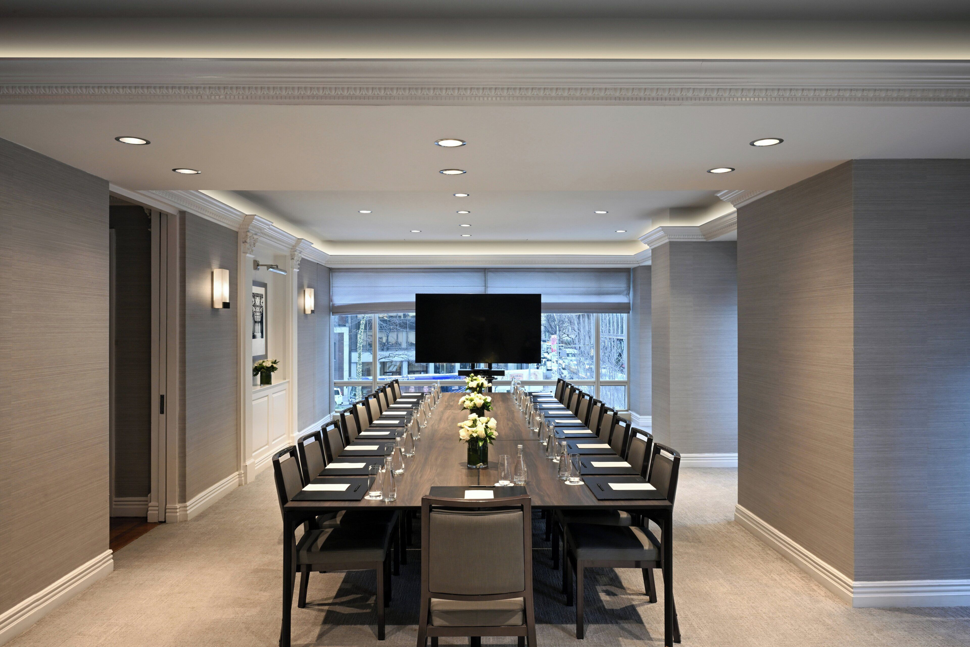 A conference room with a long table, chairs, and a flat-screen TV.