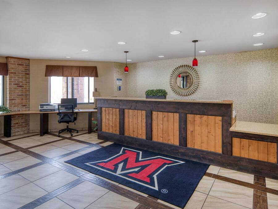 Un área de recepción con un mostrador de madera, un espejo grande y un logotipo en el suelo.
