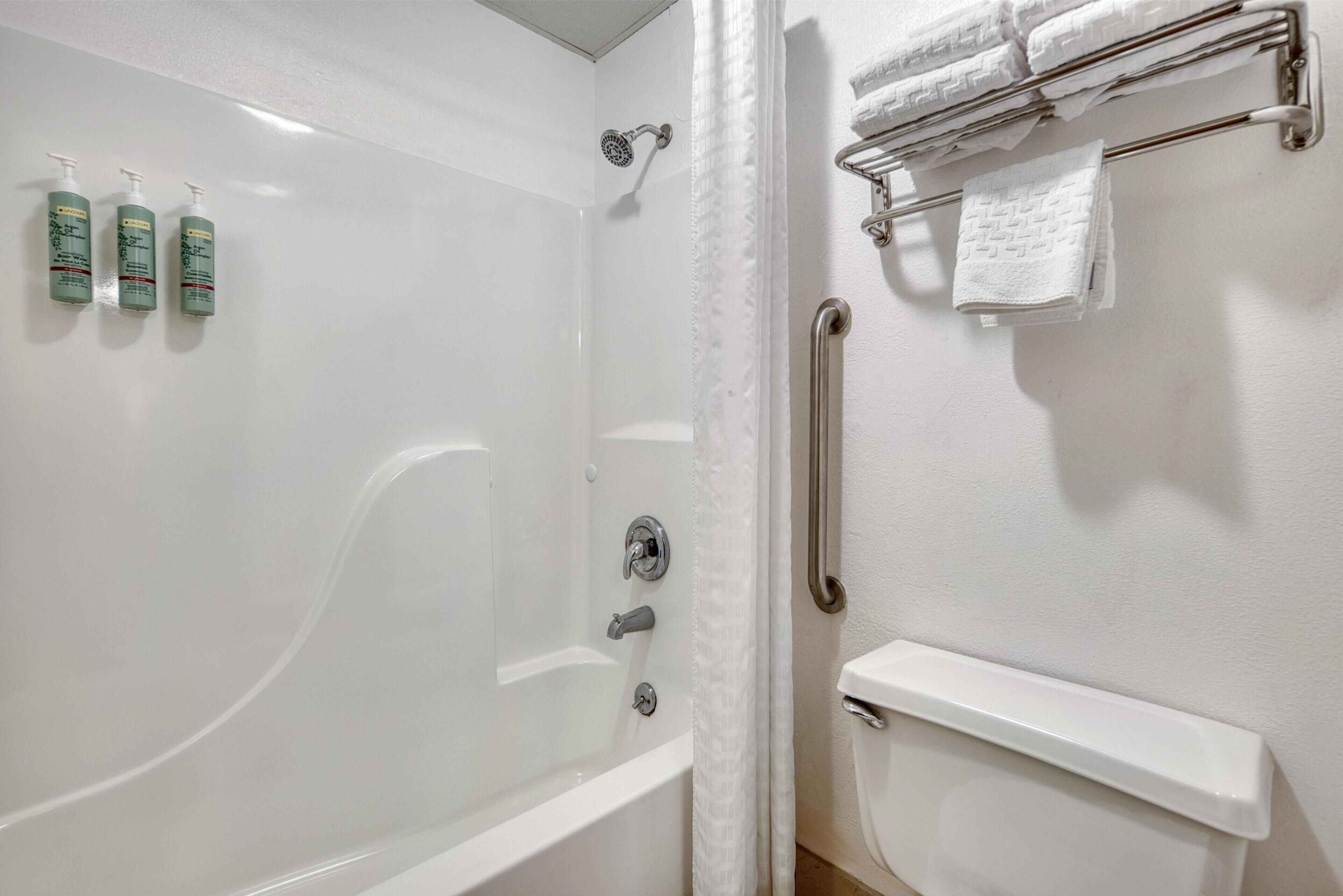 Un baño con ducha, inodoro y toallero.