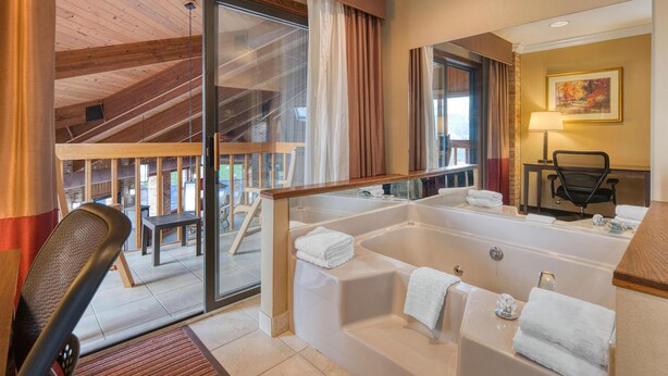 Une salle de bain moderne dotée d’une grande baignoire, d’une douche en verre et offrant une vue sur la terrasse extérieure.