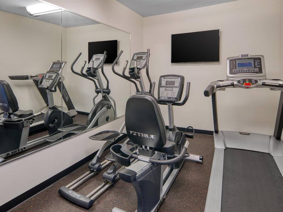 A gym with stationary bikes, a treadmill, and a mirrored wall.