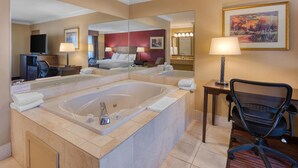 Une chambre d’hôtel avec une grande baignoire, un bureau avec une chaise, une télévision et un miroir.