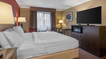 A hotel room with a bed, a desk, a television, and a microwave.
