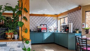 A kitchen with teal cabinets, a coffee machine, and a countertop with various appliances. - Econo Lodge Cleveland Southeast - Kent (Streetsboro)