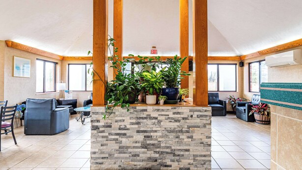 A lobby with a stone reception desk, multiple seating areas, and large windows. - Econo Lodge Cleveland Southeast - Kent (Streetsboro)