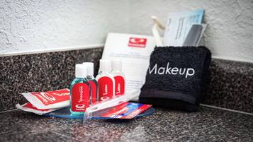 Toiletries on a granite countertop, including shampoo, lotion, and makeup.