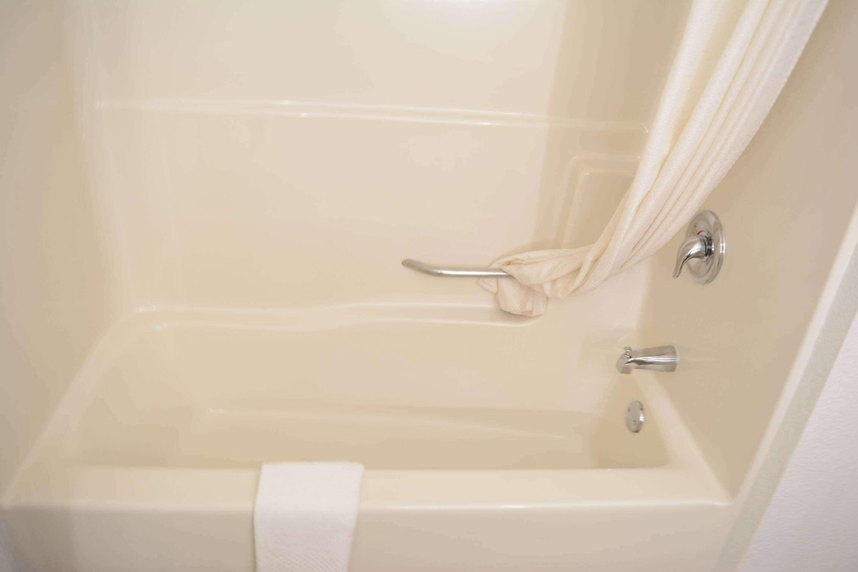 A bathtub with a shower curtain, a towel rack, and a faucet.