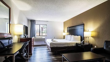 A hotel room with a bed, desk, chair, and a television.