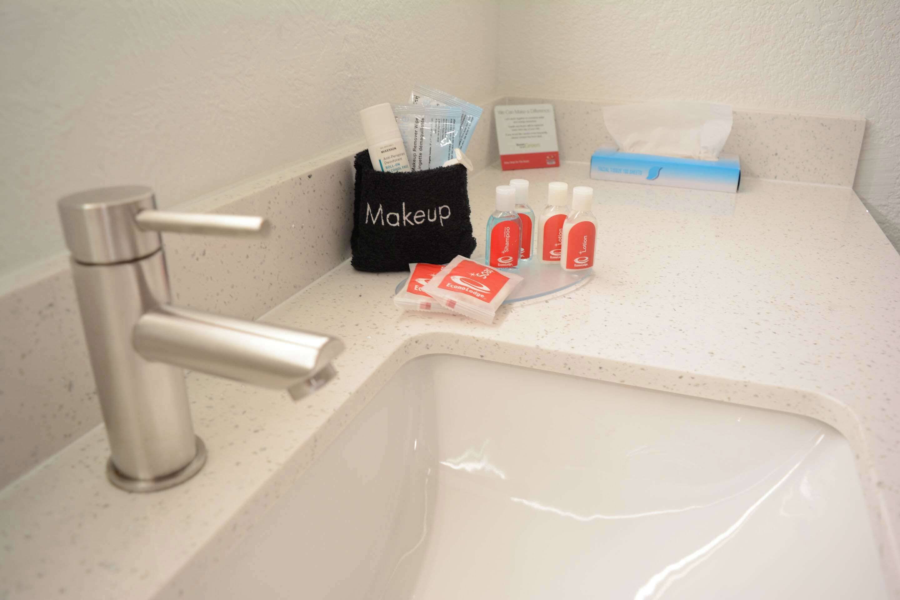 A bathroom sink with a makeup bag, tissues, and toiletries.