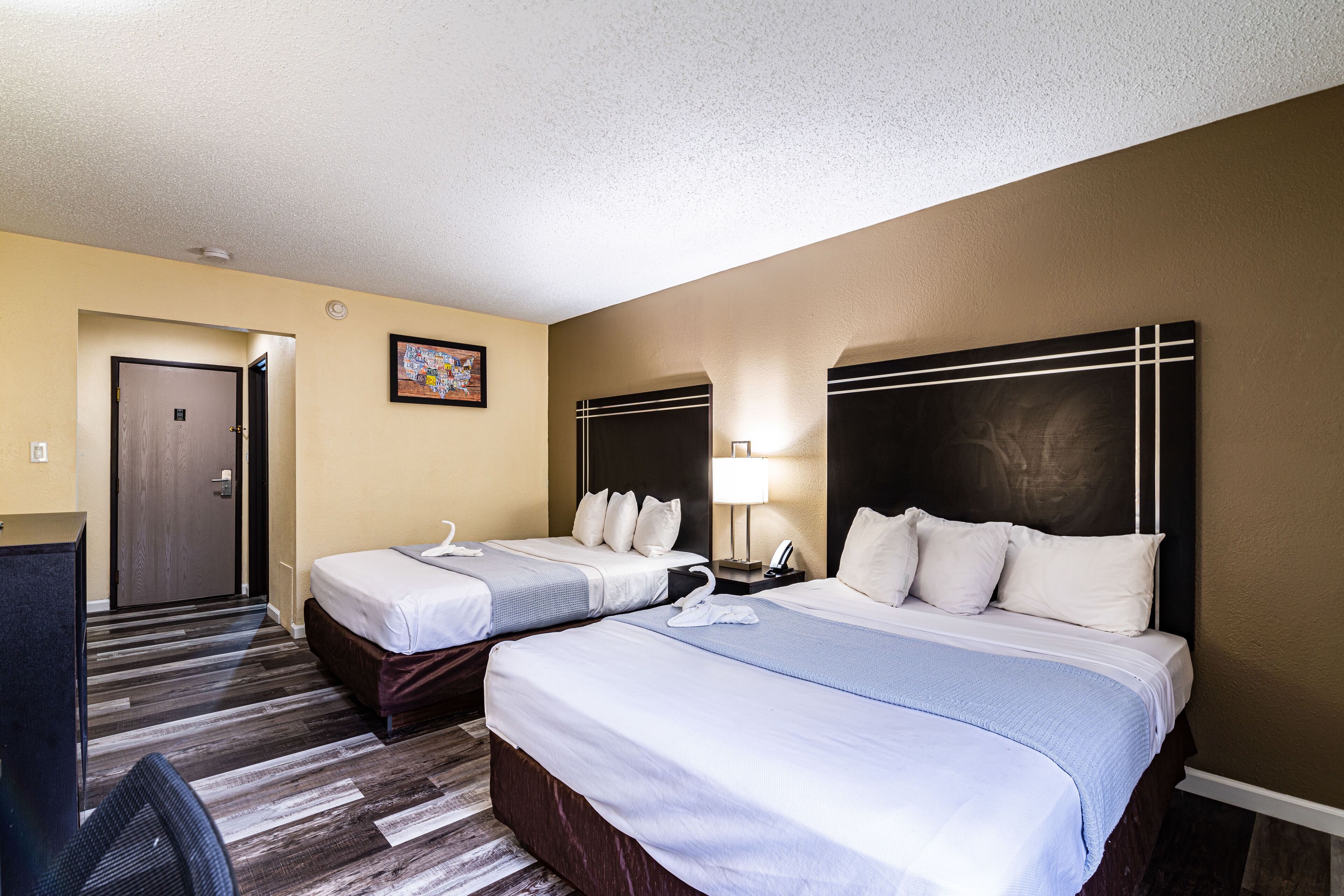 Habitación de hotel con dos camas, un escritorio y una silla.