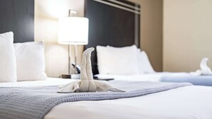 A hotel room with a neatly made bed, a bedside lamp, and a headboard. - Econo Lodge Cleveland Southeast - Kent (Streetsboro)