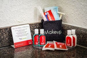 Balcão de casa de banho de hotel com produtos de higiene, um aviso sobre a poupança de água e um porta-toalhas.