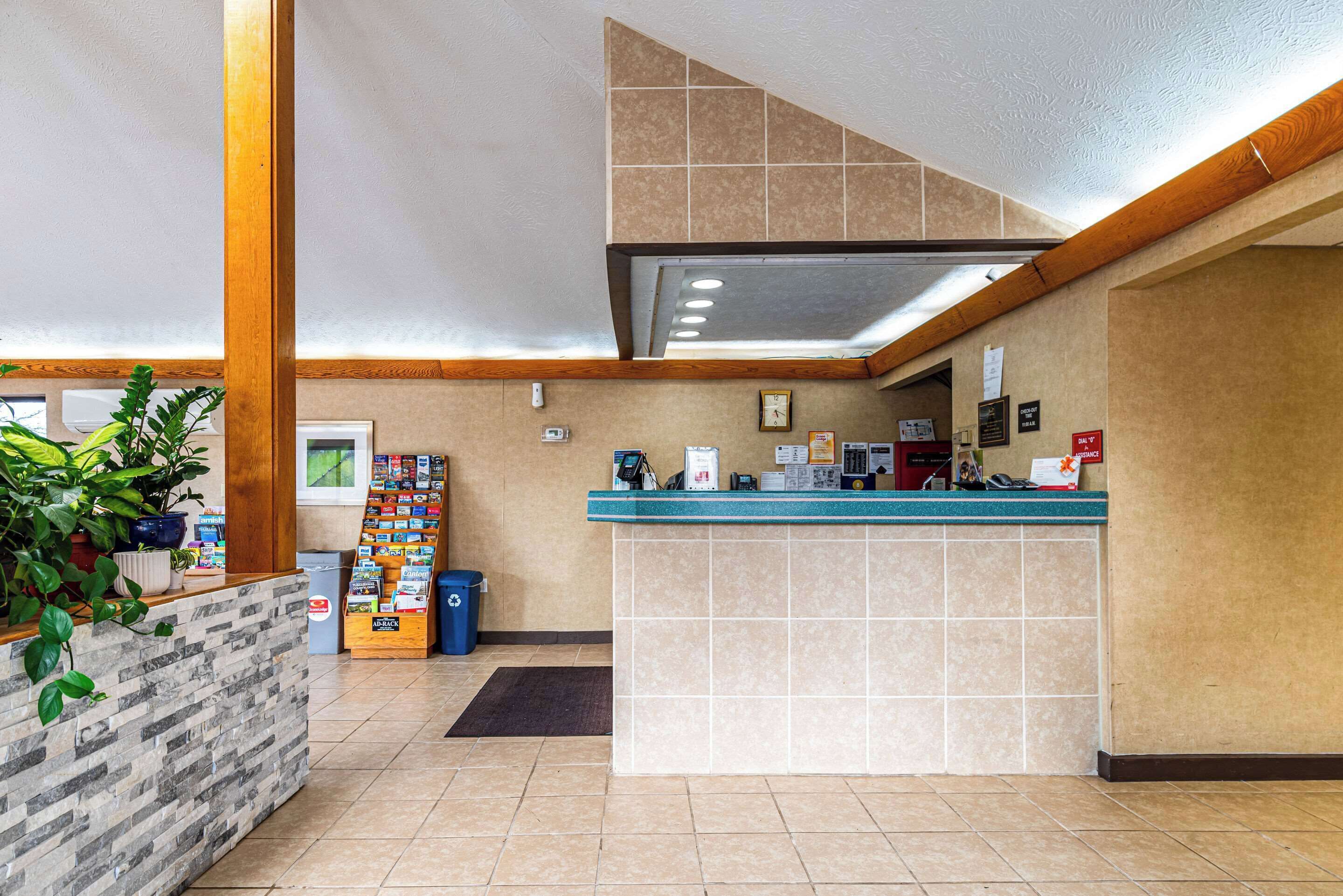 A reception area with a counter, a waste bin, a plant, and a magazine rack.