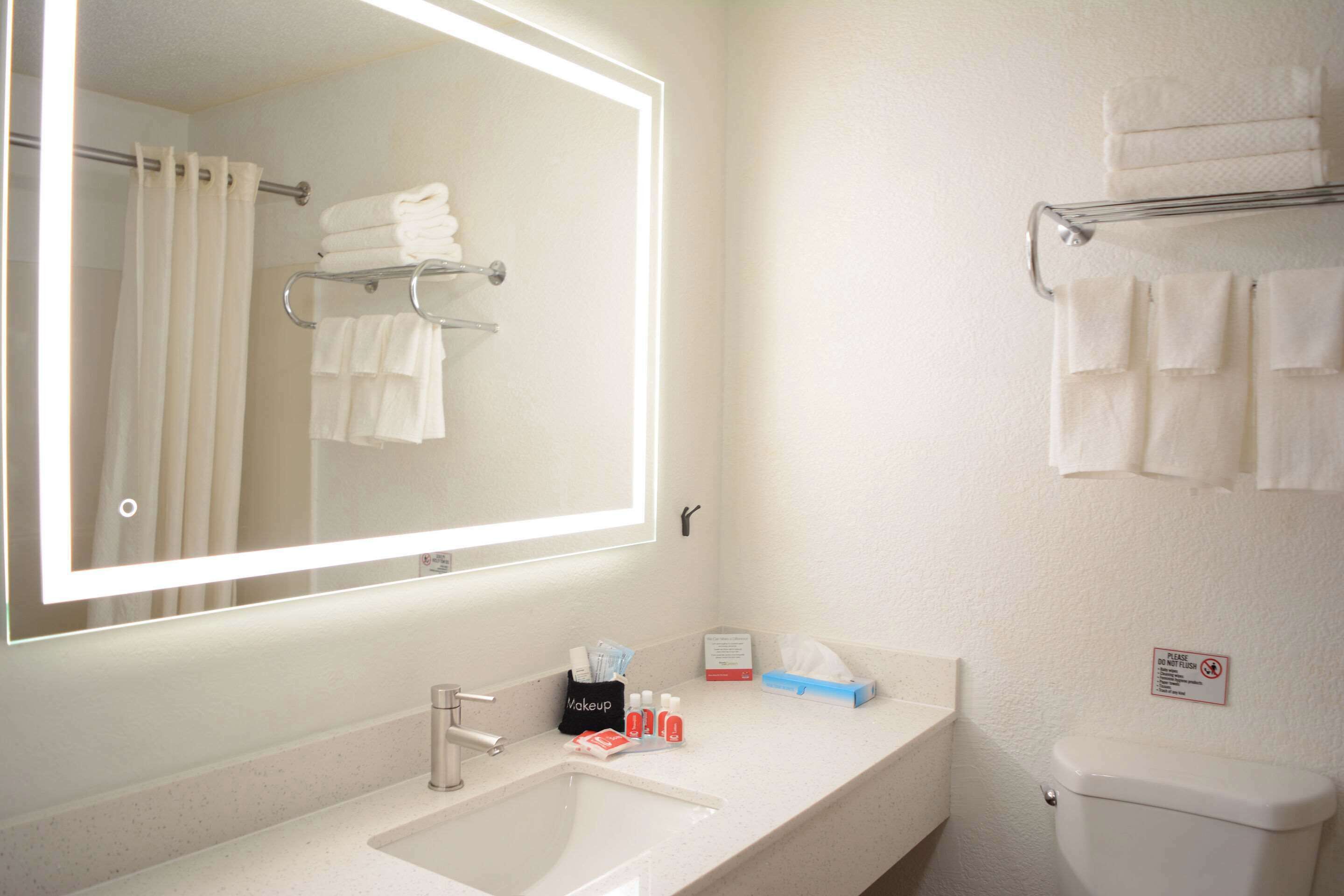 A bathroom with a sink, mirror, towel rack, and toilet.