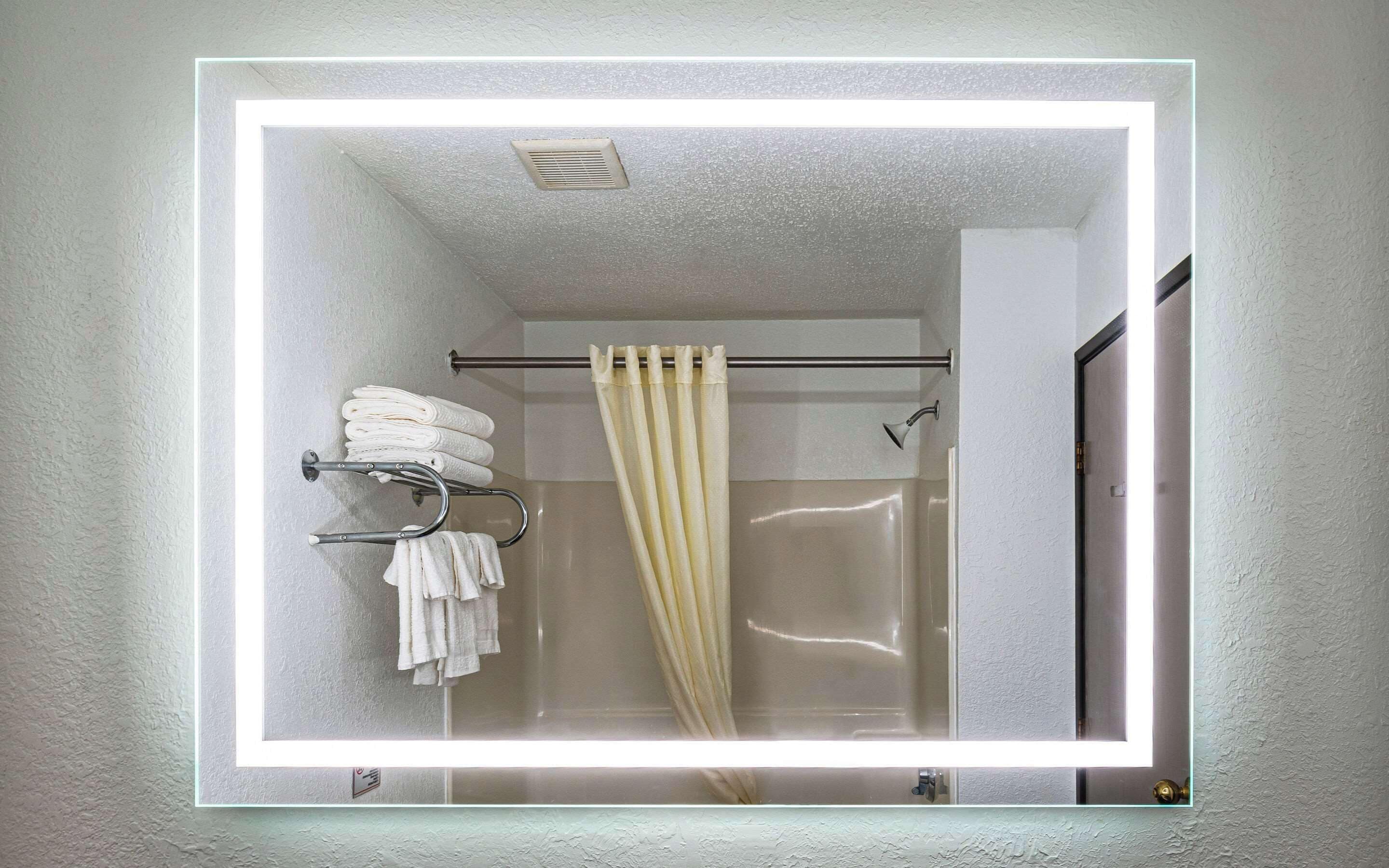A bathroom with a glass shower enclosure, a towel rack with folded towels, and a showerhead.