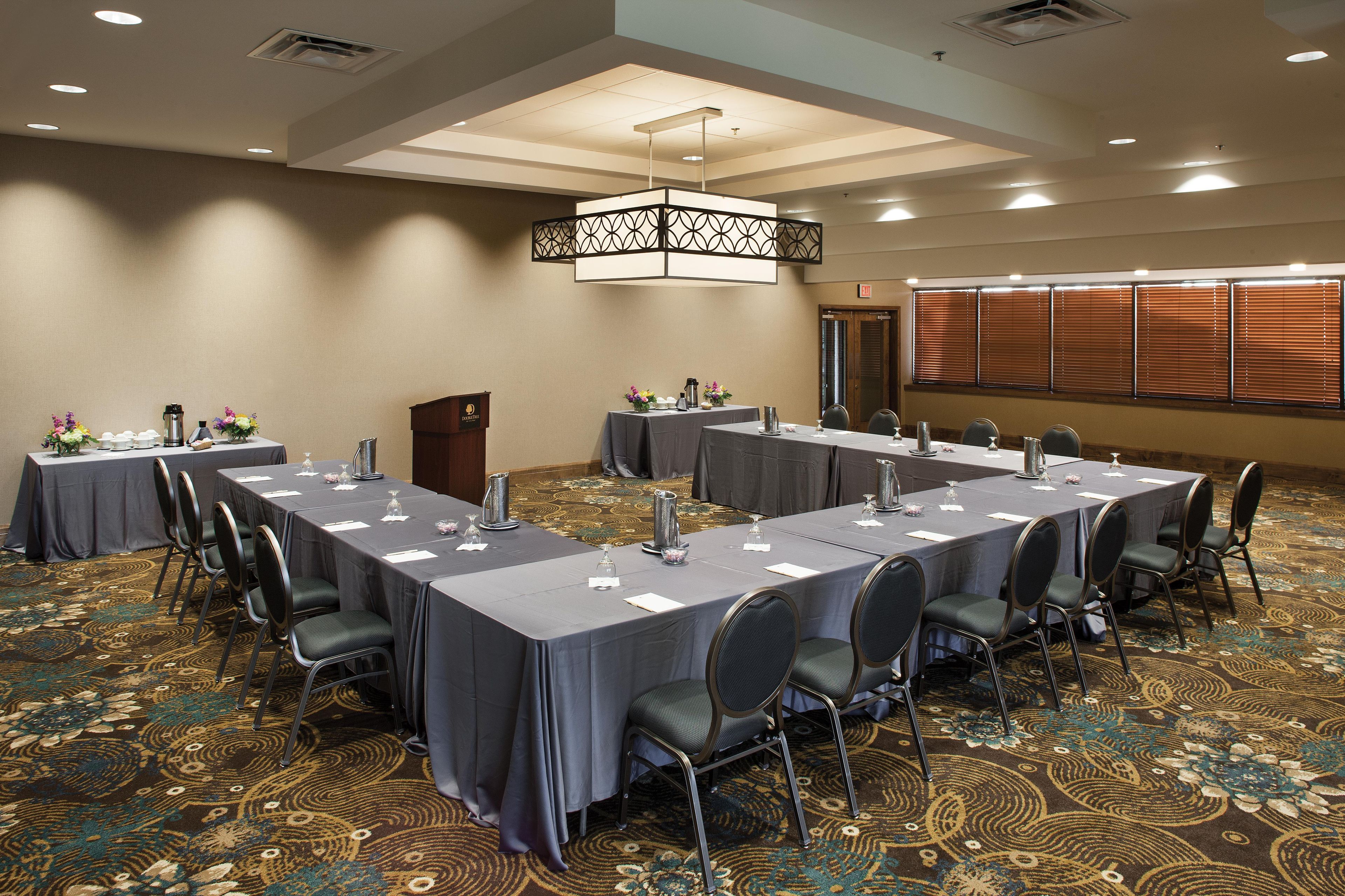 A conference room with multiple tables, chairs, and a podium.
