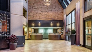Un hall con pared de ladrillo, mostrador de recepción y un ventanal grande.