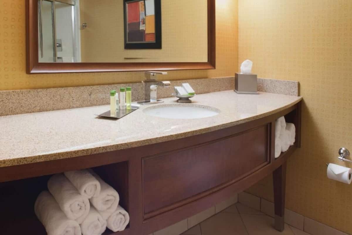 A hotel bathroom with a large mirror, a sink, and a towel rack.
