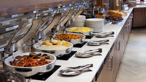 A buffet with various food items and serving utensils. - DoubleTree by Hilton Hotel Johnson City (Johnson City)