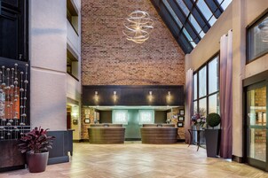 Um saguão de hotel com parede de tijolos, balcão de recepção e um grande candelabro.