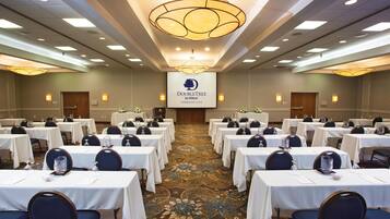 A conference room with tables, chairs, and a large screen displaying the hotel name.
