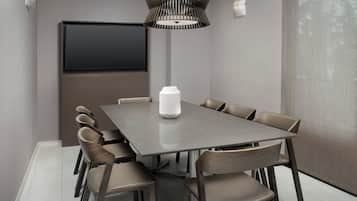 Een moderne eetruimte met een rechthoekige tafel, zes stoelen, een witte vaas, een groot scherm en een bijzondere hanglamp.