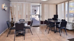 Una camera d'albergo con zona pranzo, un'ampia finestra con tende, una TV a schermo piatto e un termosifone.