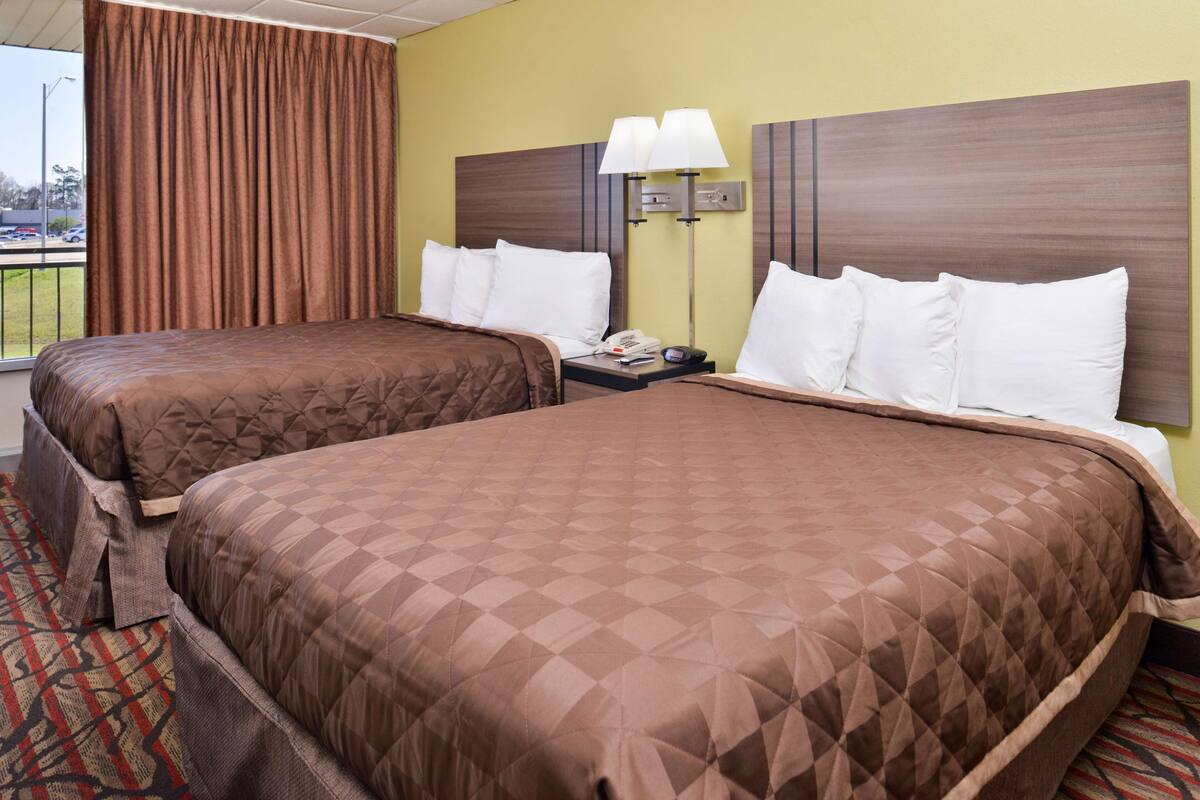 Een hotelkamer met twee bedden, een nachtkastje, een lamp en uitzicht.