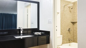 A bathroom with a black sink, a mirror, a white toilet, and a shower with a gold speckled wall. - Rodeway Inn Asheboro (Asheboro)