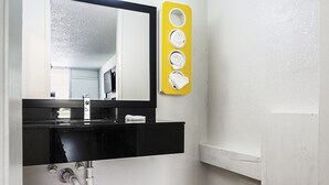 A bathroom with a black sink, a mirror, and a yellow towel rack with four towels. - Rodeway Inn Asheboro (Asheboro)