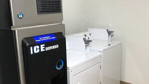 A compact, modern laundry facility with a black ice dispenser and a white washing machine. - Rodeway Inn Asheboro (Asheboro)