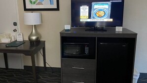 A hotel room with a television displaying a coin grading service, a lamp, a microwave, and a mini-fridge. - Rodeway Inn Asheboro (Asheboro)