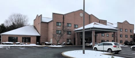 A multi-story brick building with a covered entrance and a parking lot.