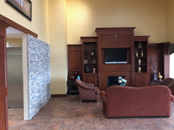 A living room with a fireplace, a television, and a stone accent wall.