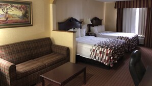 A hotel room with a sofa, two beds, a desk, and a painting on the wall. - Red Roof Inn & Suites Chestertown (Chestertown)