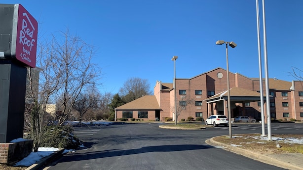 A hotel entrance with a clear sky, a parking lot, and a brick building with a covered entrance. - Red Roof Inn & Suites Chestertown (Chestertown)