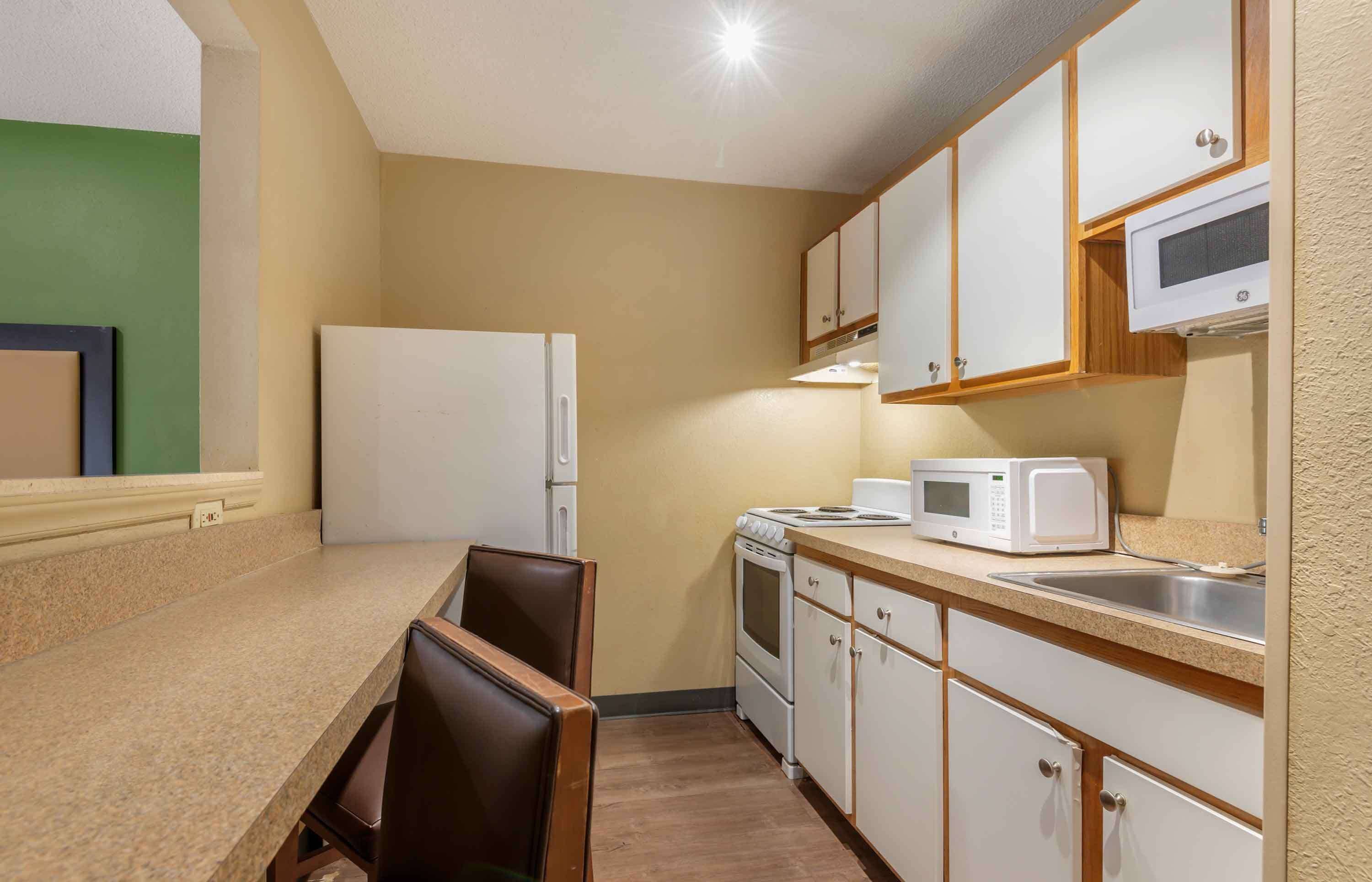A compact kitchen with a refrigerator, microwave, stove, and cabinets.