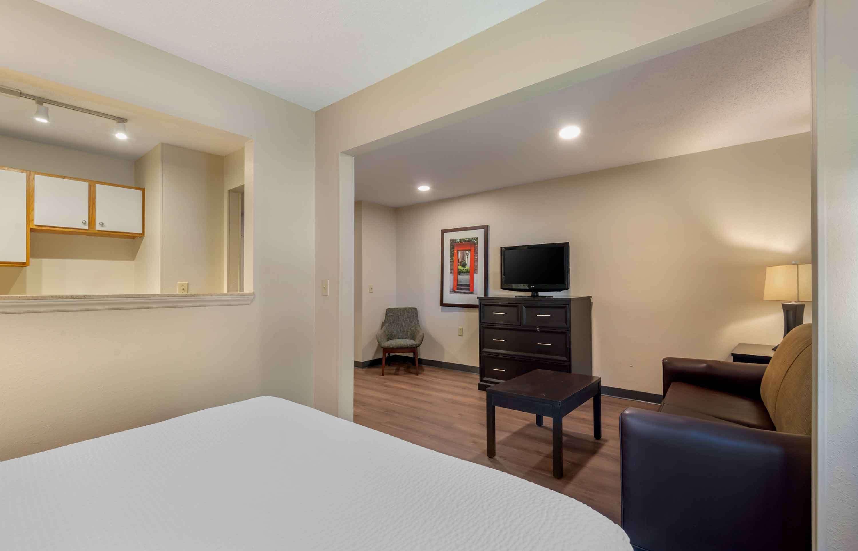 A hotel room with a bed, a TV, a desk, a chair, and a sofa.