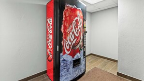 Un distributeur automatique situé dans un couloir, orné du logo Coca-Cola Classic.