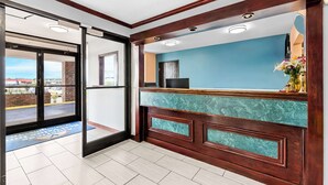 Un espace d’accueil avec un mur bleu, un comptoir de réception en bois et une vue à travers la porte vitrée.