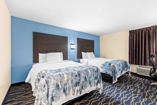 A hotel room with two beds, a wall-mounted air conditioning unit, and a patterned carpet. - Americas Best Value Inn McMinnville (McMinnville)