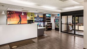 A reception area with a modern design, including a reception desk, a digital screen, and a wall with colorful artwork. - Clarion pointe near I-75 (Forsyth)