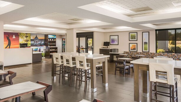 A spacious indoor area with multiple seating arrangements, including bar stools and tables, and a variety of wall art and decorations. - Clarion pointe near I-75 (Forsyth)