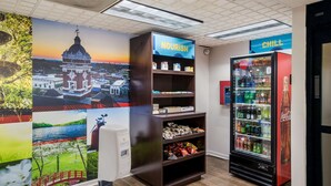A wall with a large mural, a vending machine, and a shelf unit with snacks. - Clarion pointe near I-75 (Forsyth)