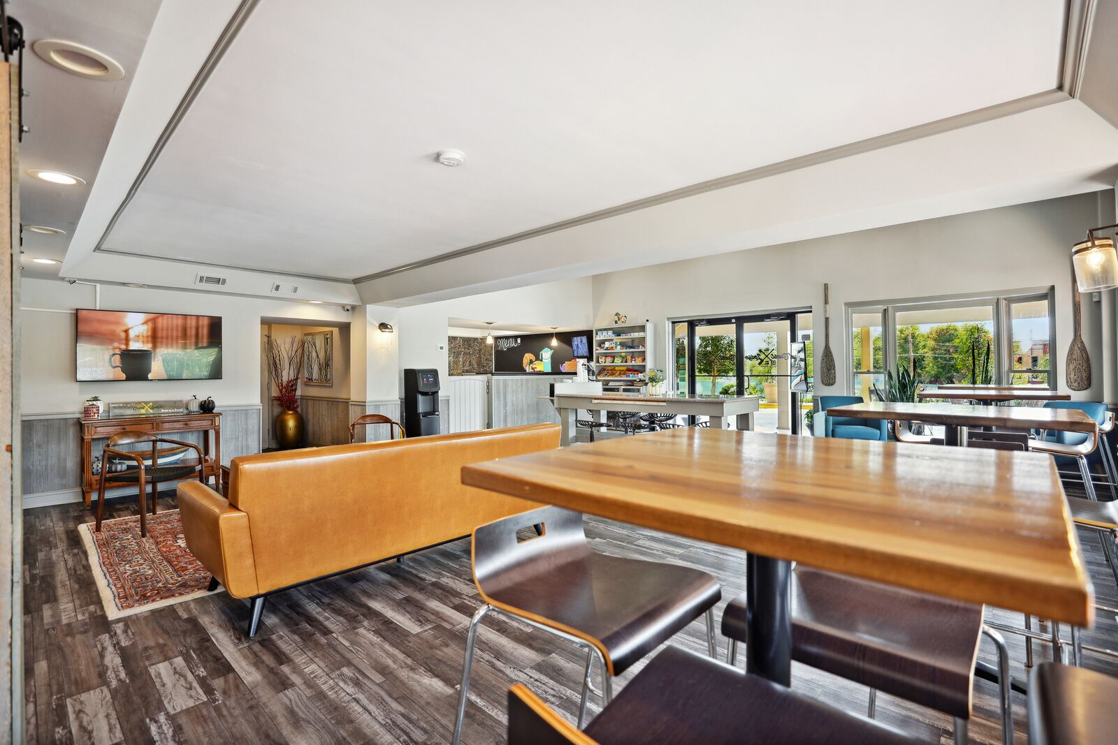 Una cocina moderna con comedor, suelo de madera y ventanas amplias con vistas al exterior.